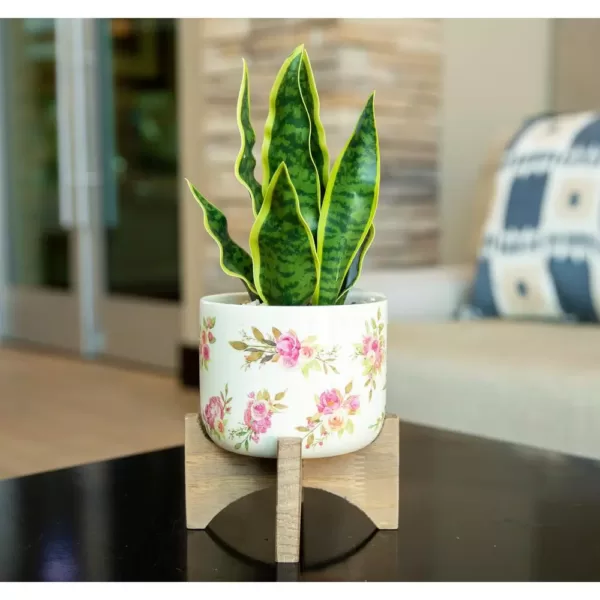 Flora Bunda 12 in. Faux Snake Plant in Flower Print White Ceramic Pot on Wood Stand